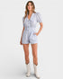Woman wearing a light blue striped romper with white boots on a white background