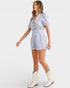 Woman wearing a light blue striped romper with white boots on a white background