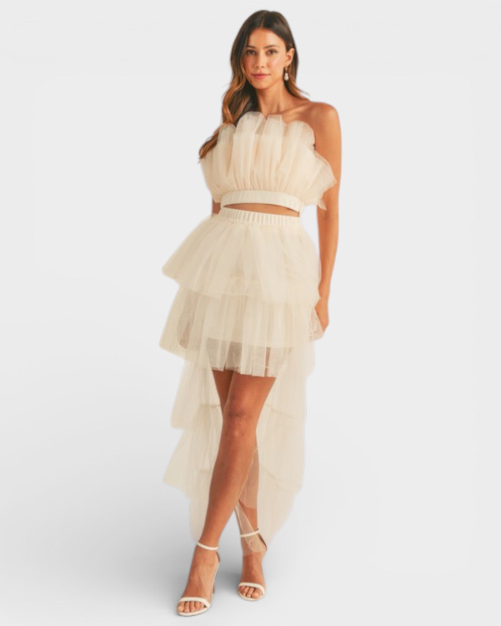 Woman wearing a two-piece outfit with a top and high-low skirt on a white background