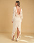 Woman wearing a white dress with a open back on a beige background