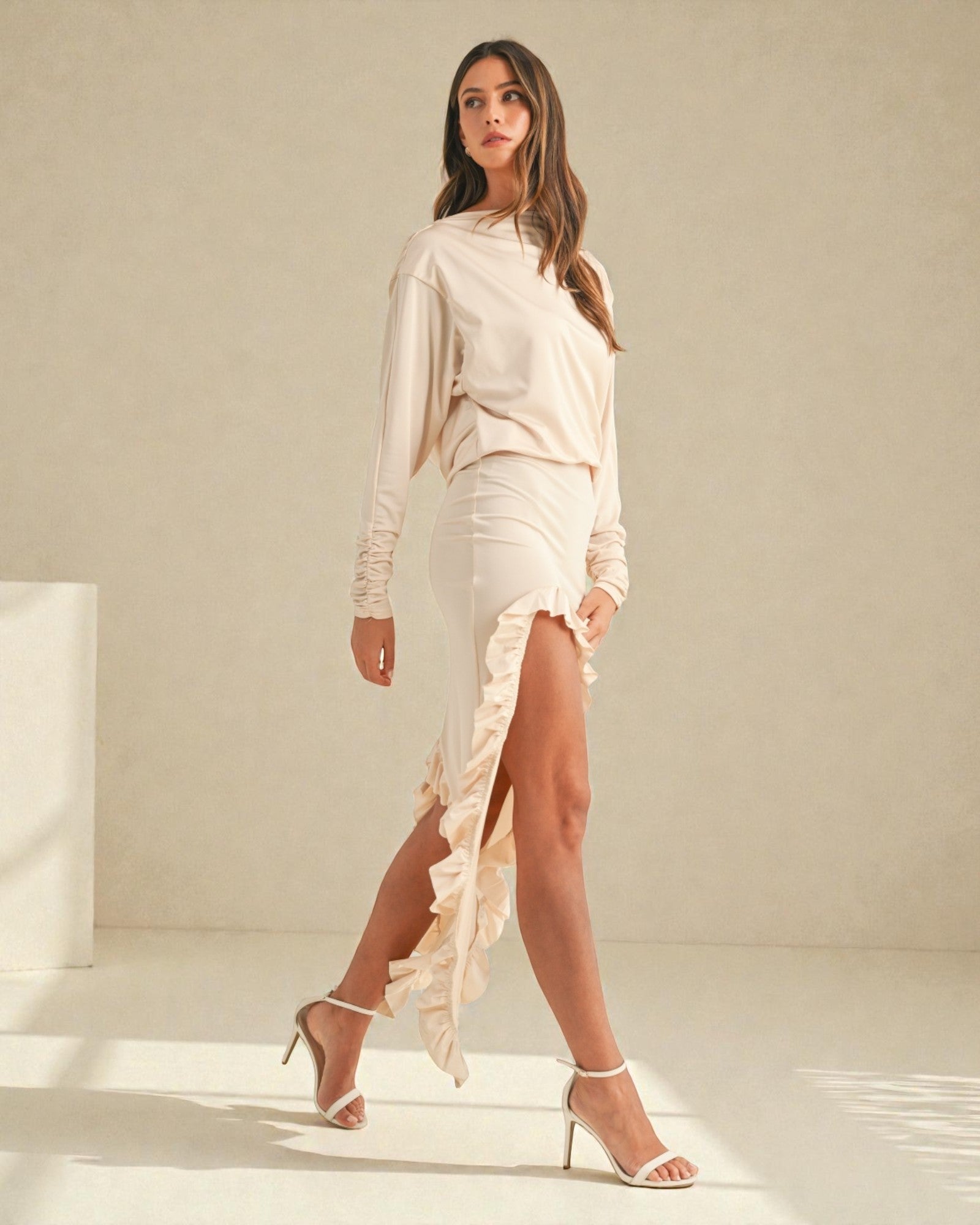 Woman wearing a light-colored dress with a slit on a neutral background