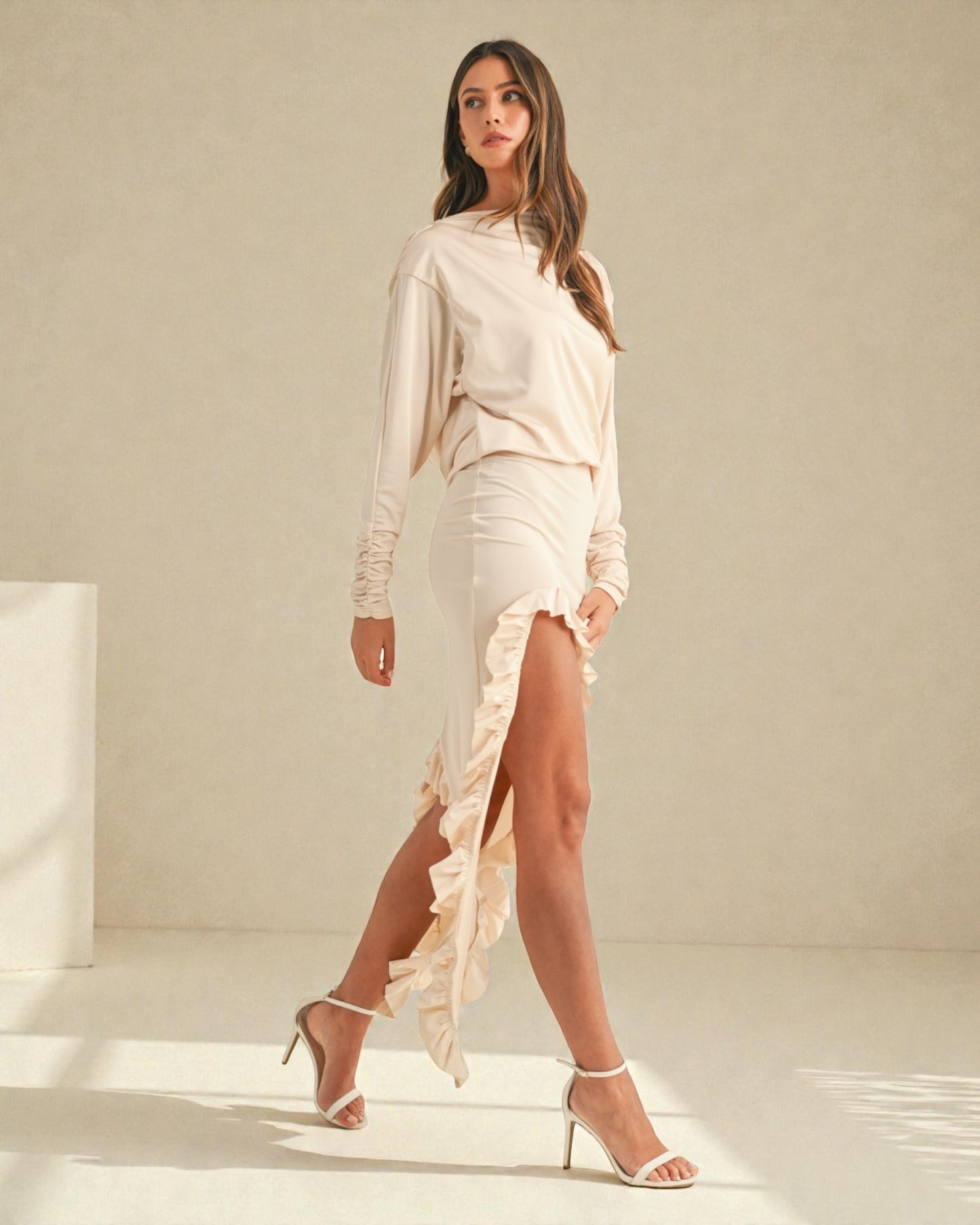 Woman wearing a light-colored dress with a slit on a neutral background