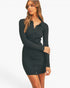 A woman modeling a black ribbed long-sleeve button-front mini dress against a plain light gray studio background.