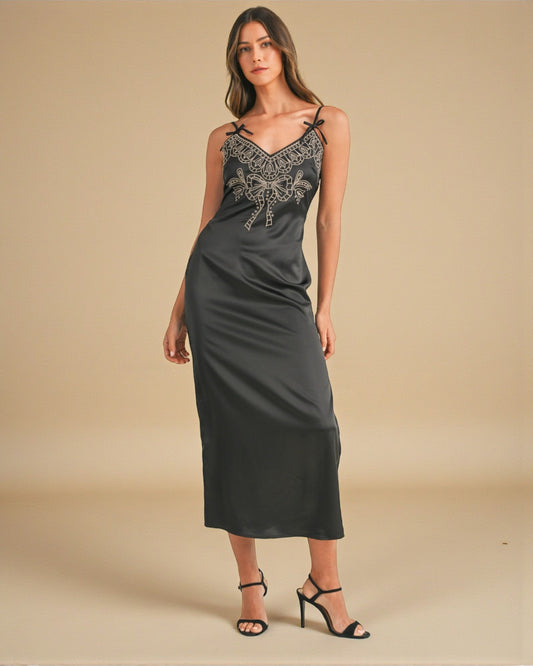 Woman wearing a dark gray slip dress with lace detailing on a beige background