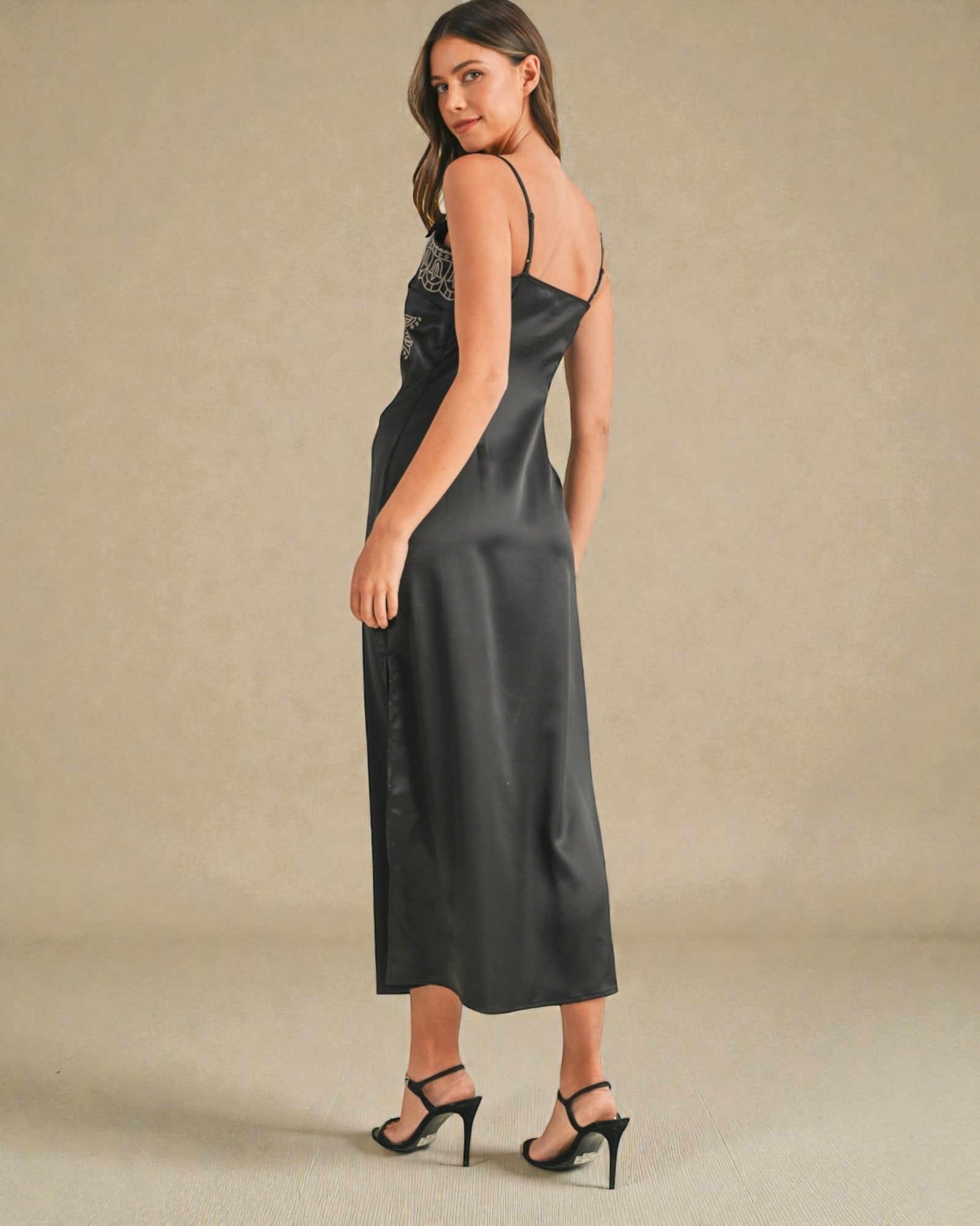 Woman wearing a black satin slip dress with a beige background