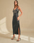 Woman wearing a black satin slip dress with lace detailing on a beige background