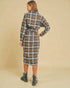 Woman wearing a plaid dress with a belt on a beige background