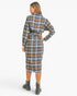 A woman shown from the back wearing a long-sleeve plaid shirt dress with a matching tie belt, paired with dark combat boots, against a plain white studio background.