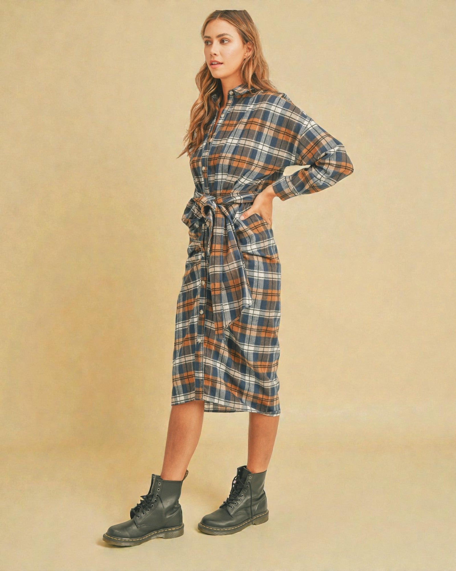 Woman wearing a plaid dress with long sleeves on a beige background