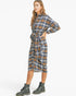 A woman modeling a long-sleeve plaid shirt dress with a tie waist, shown in profile against a plain white studio background. She is wearing dark green combat boots.