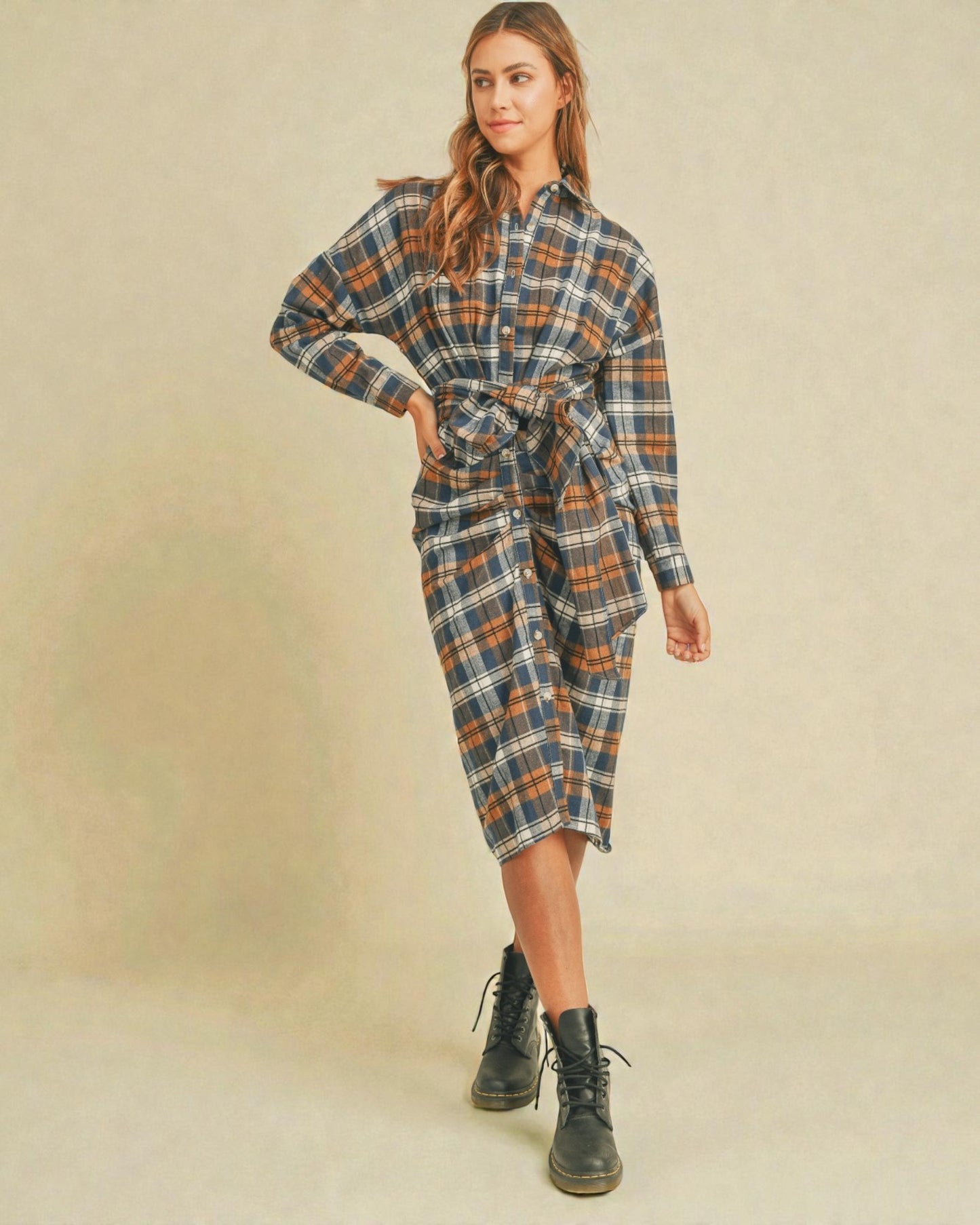 Woman wearing a plaid dress with a belt on a beige background
