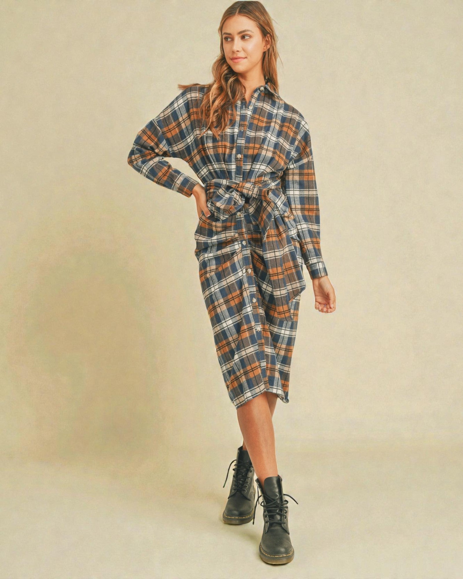 Woman wearing a plaid dress with a belt on a beige background