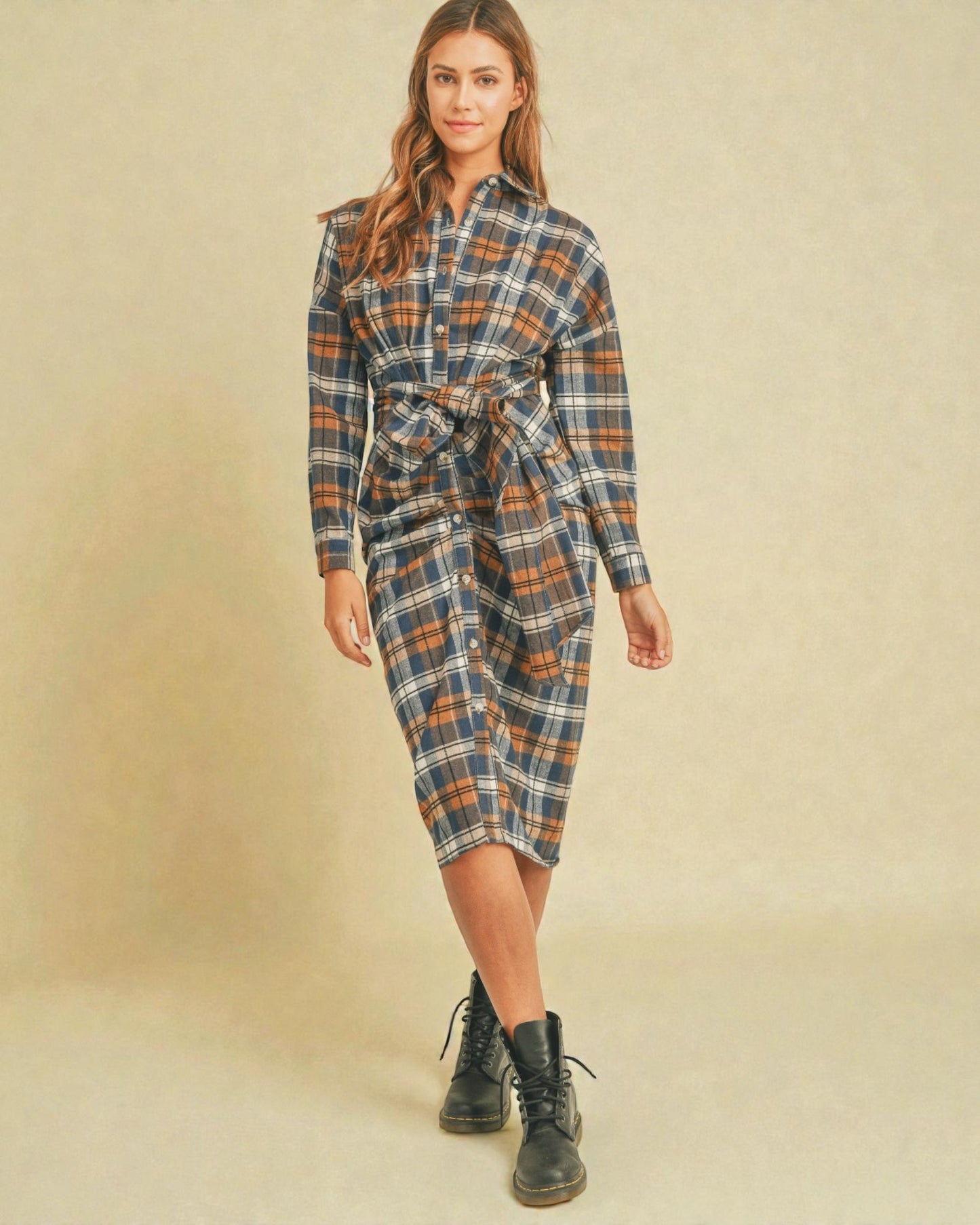 Woman wearing a plaid dress with a belt on a beige background