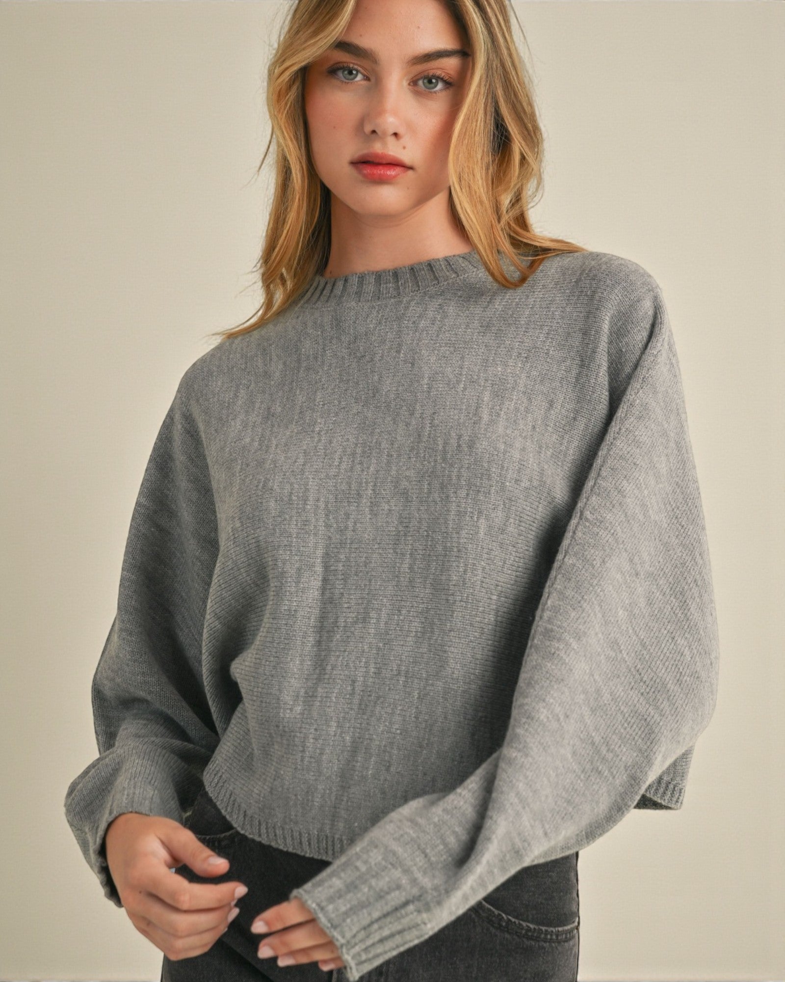 Woman wearing a gray sweater against a neutral background