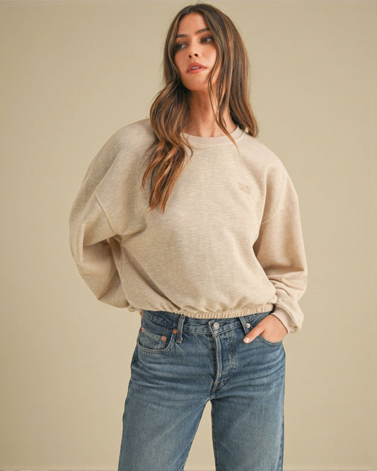 Woman wearing a beige sweater and blue jeans against a beige background