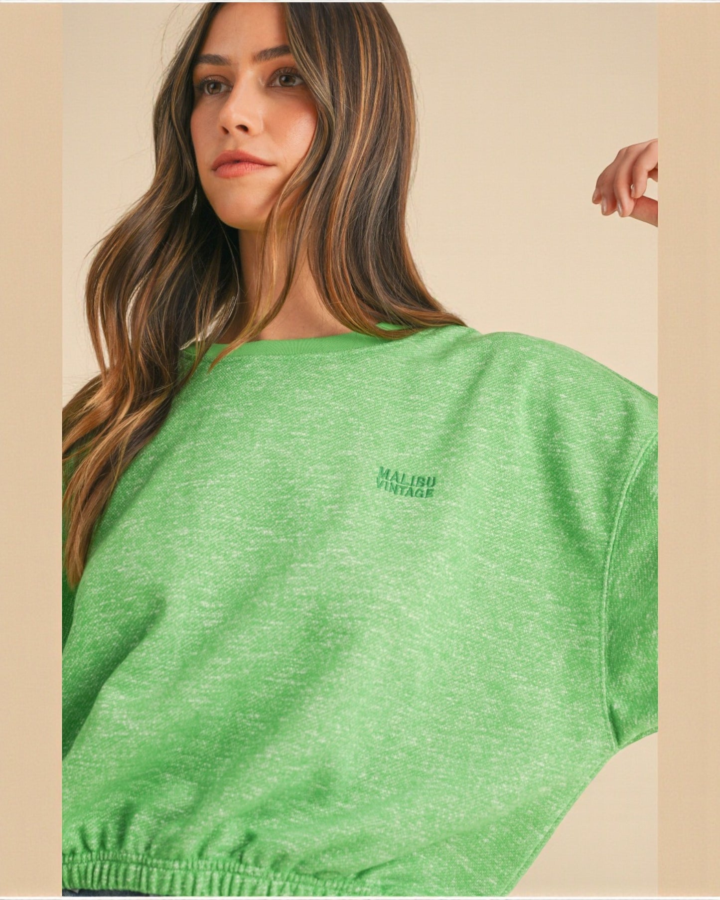 Woman wearing a green t-shirt with a logo on a beige background