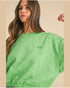Woman wearing a green t-shirt with a logo on a beige background