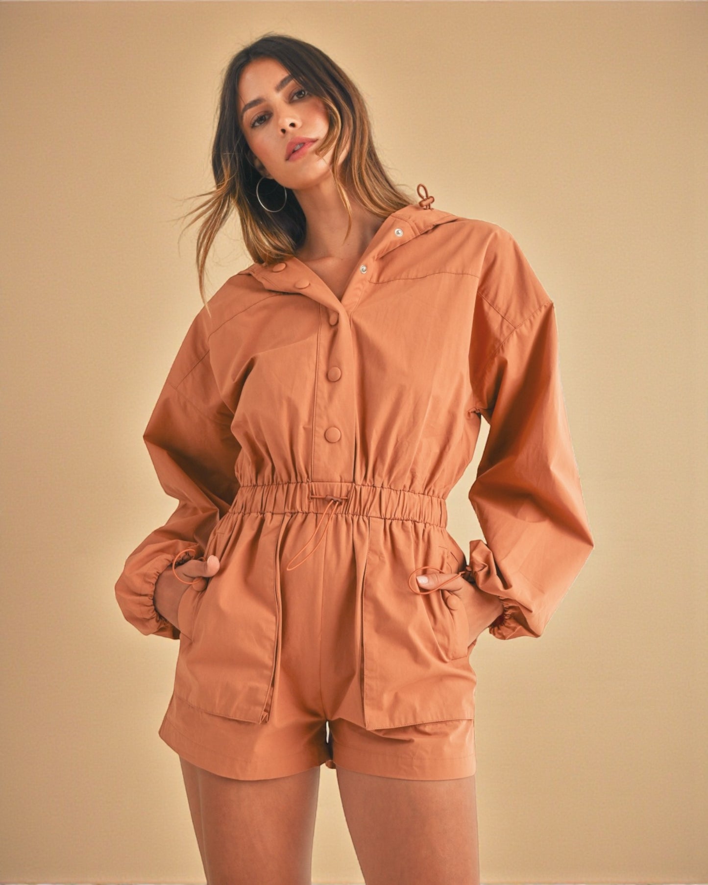 Woman wearing a brown romper against a beige background