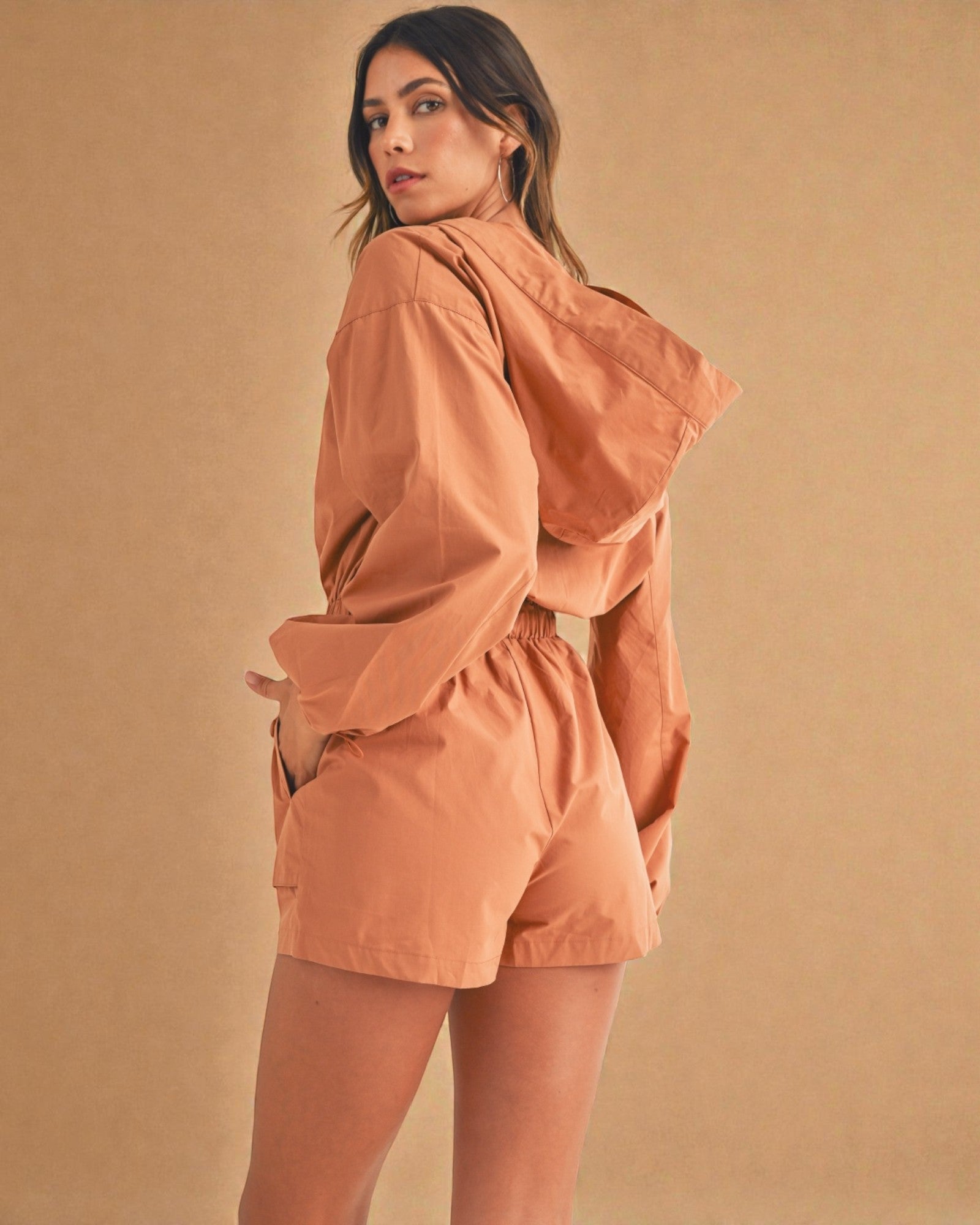Woman wearing a peach-colored outfit against a matching background