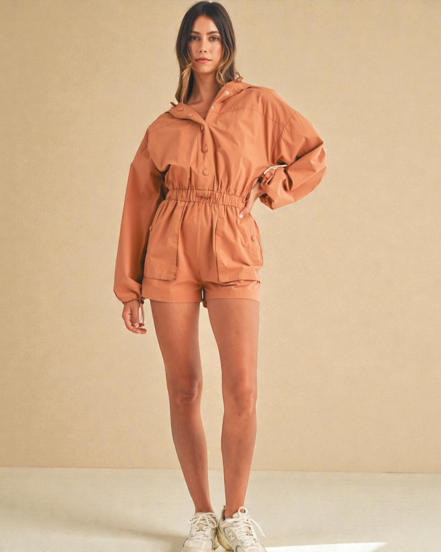 Woman wearing a brown tracksuit against a beige background