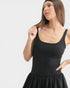 Woman wearing a black sleeveless dress against a white background
