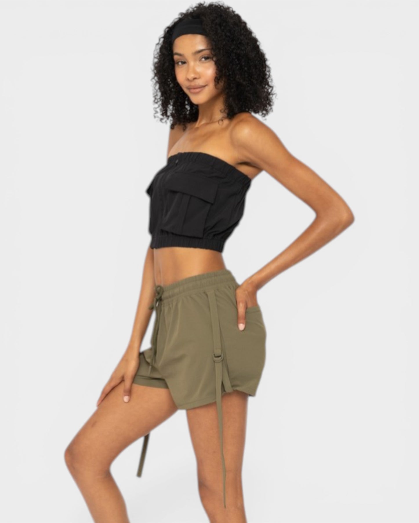 Woman wearing a black strapless top and green shorts on a white background