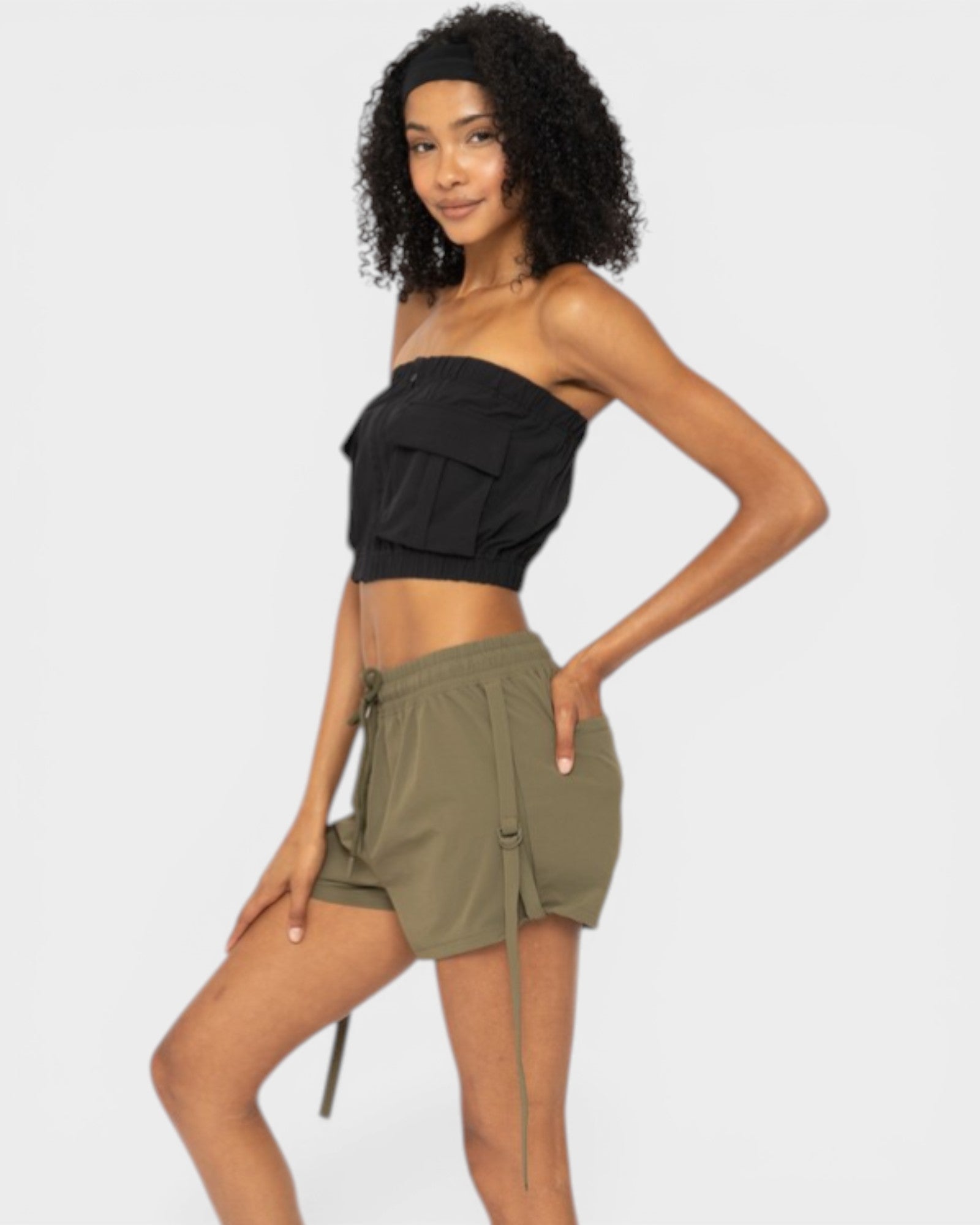 Woman wearing a black strapless top and green shorts on a white background
