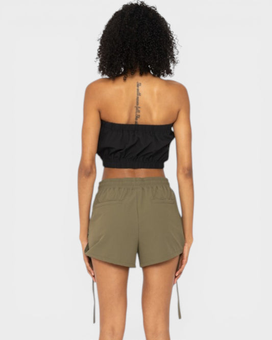 Person wearing a black strapless top and olive green shorts on a white background