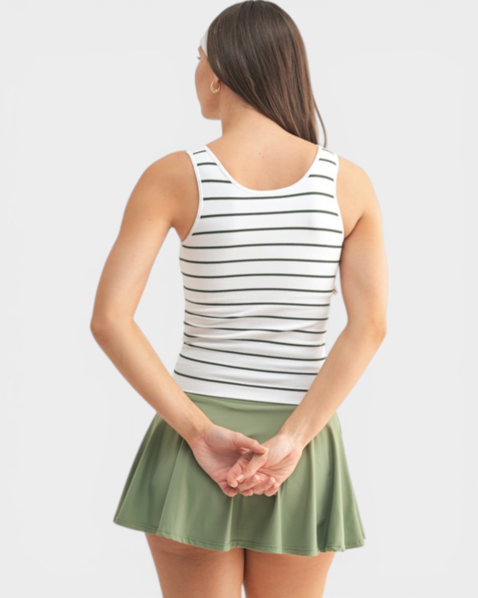 Woman wearing a striped tank top and green skirt on a white background