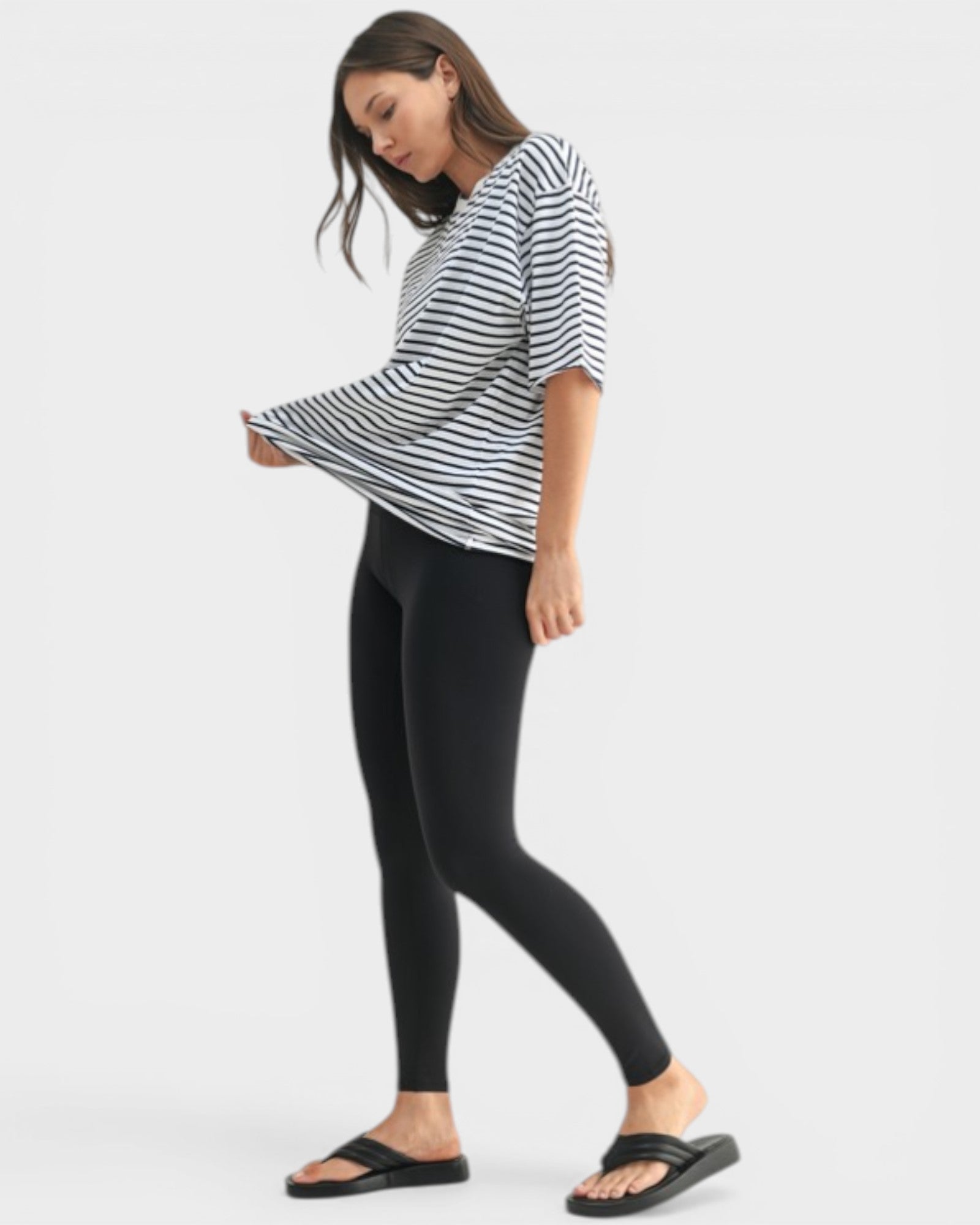 Woman wearing a black and white striped shirt and black leggings on a white background
