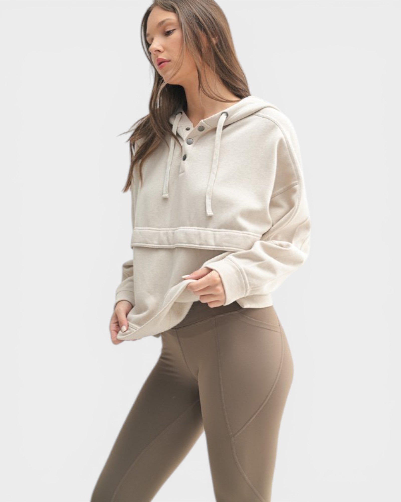 Woman wearing a beige hoodie and leggings on a white background