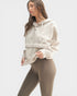 Woman wearing a beige hoodie and leggings on a white background