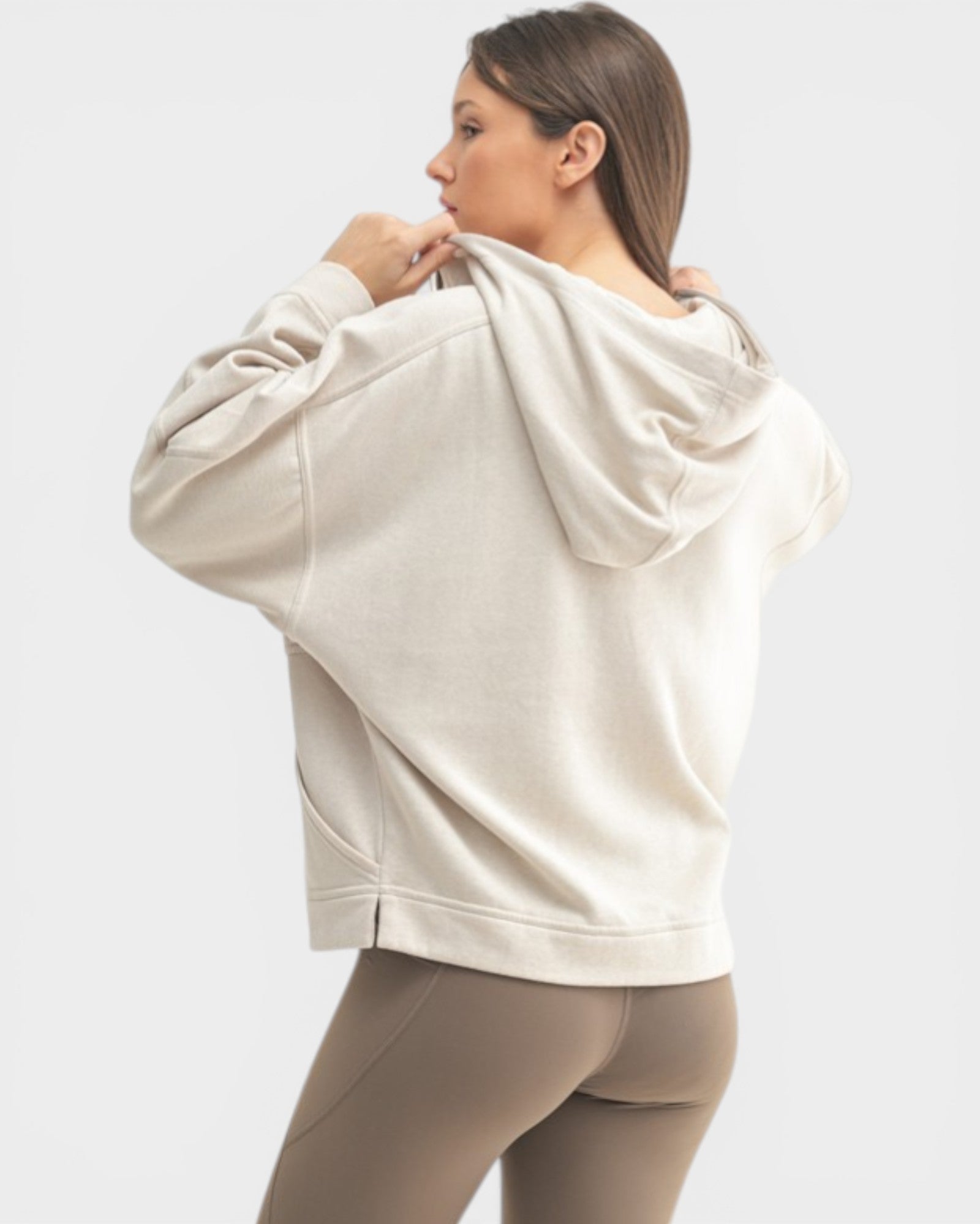 Woman wearing a beige hoodie and leggings on a white background