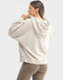 Woman wearing a beige hoodie and leggings on a white background