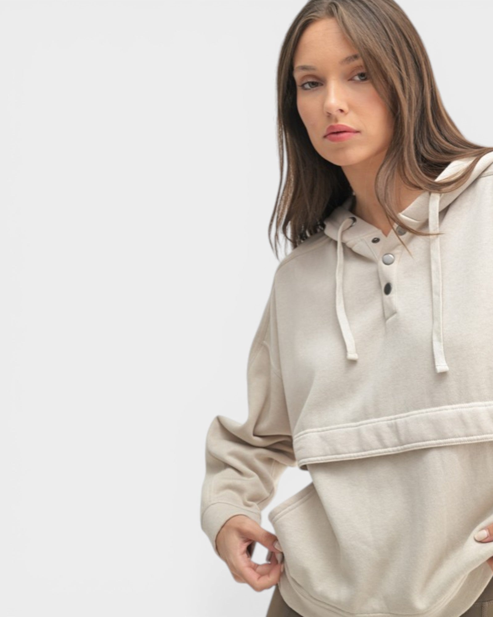 Woman wearing a beige hoodie on a light gray background