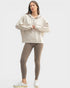 Woman wearing a beige hoodie and leggings on a white background