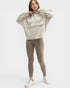 Woman wearing a beige hoodie and leggings set on a white background