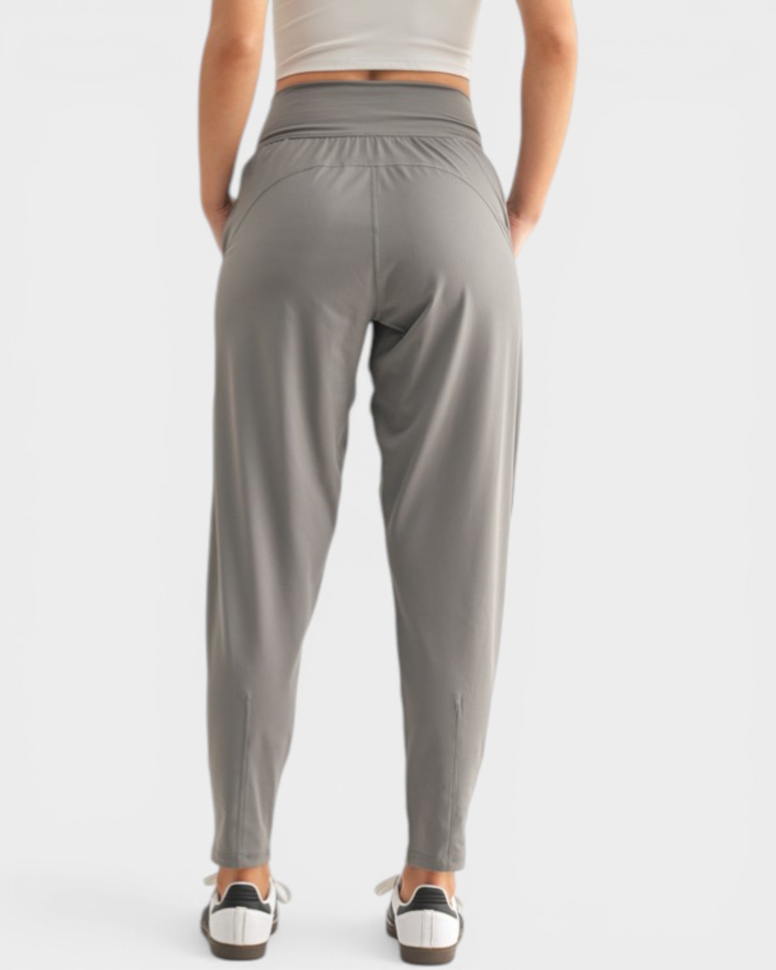 Person wearing gray high-waisted pants on a white background