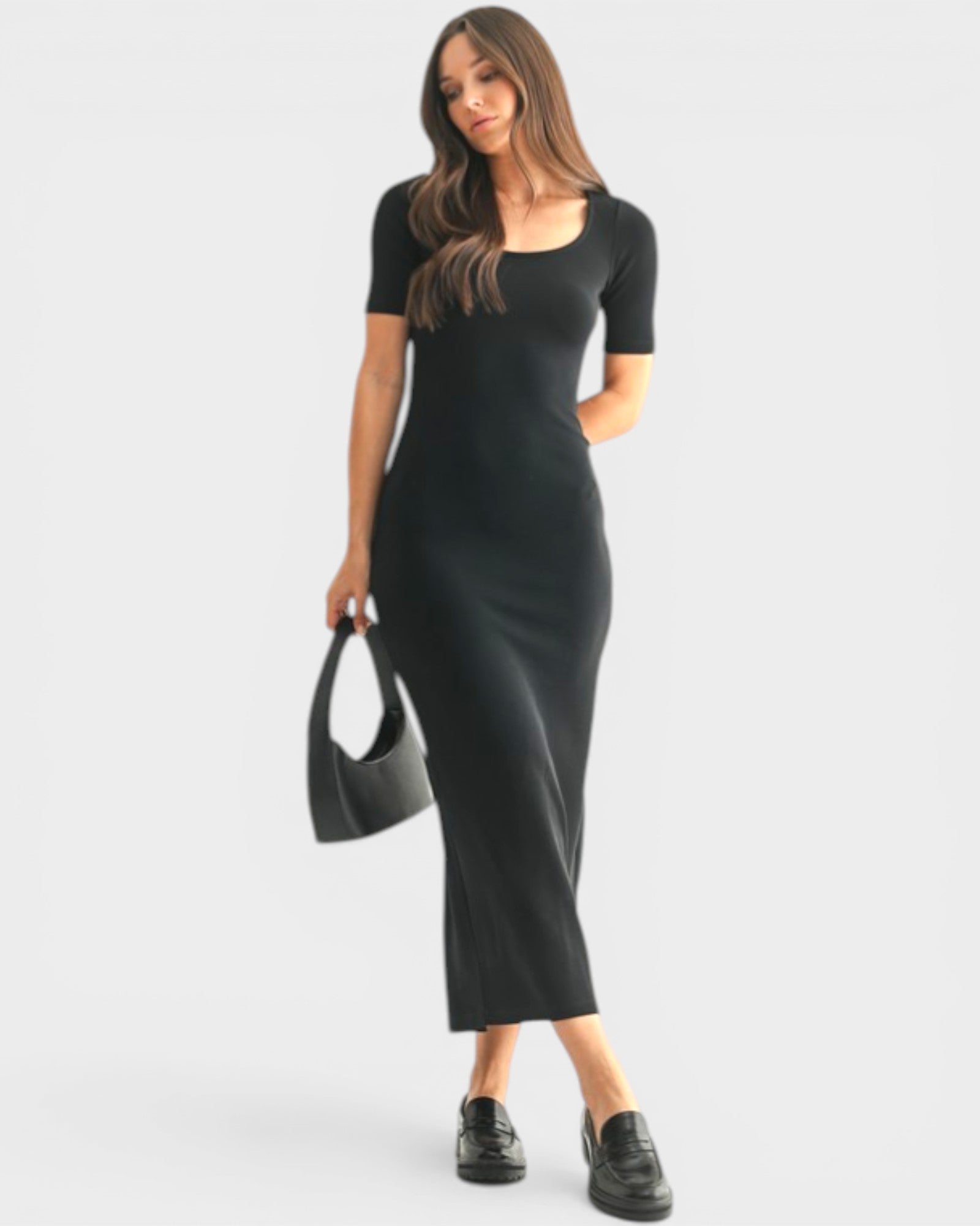 Woman wearing a black dress holding a matching handbag on a white background