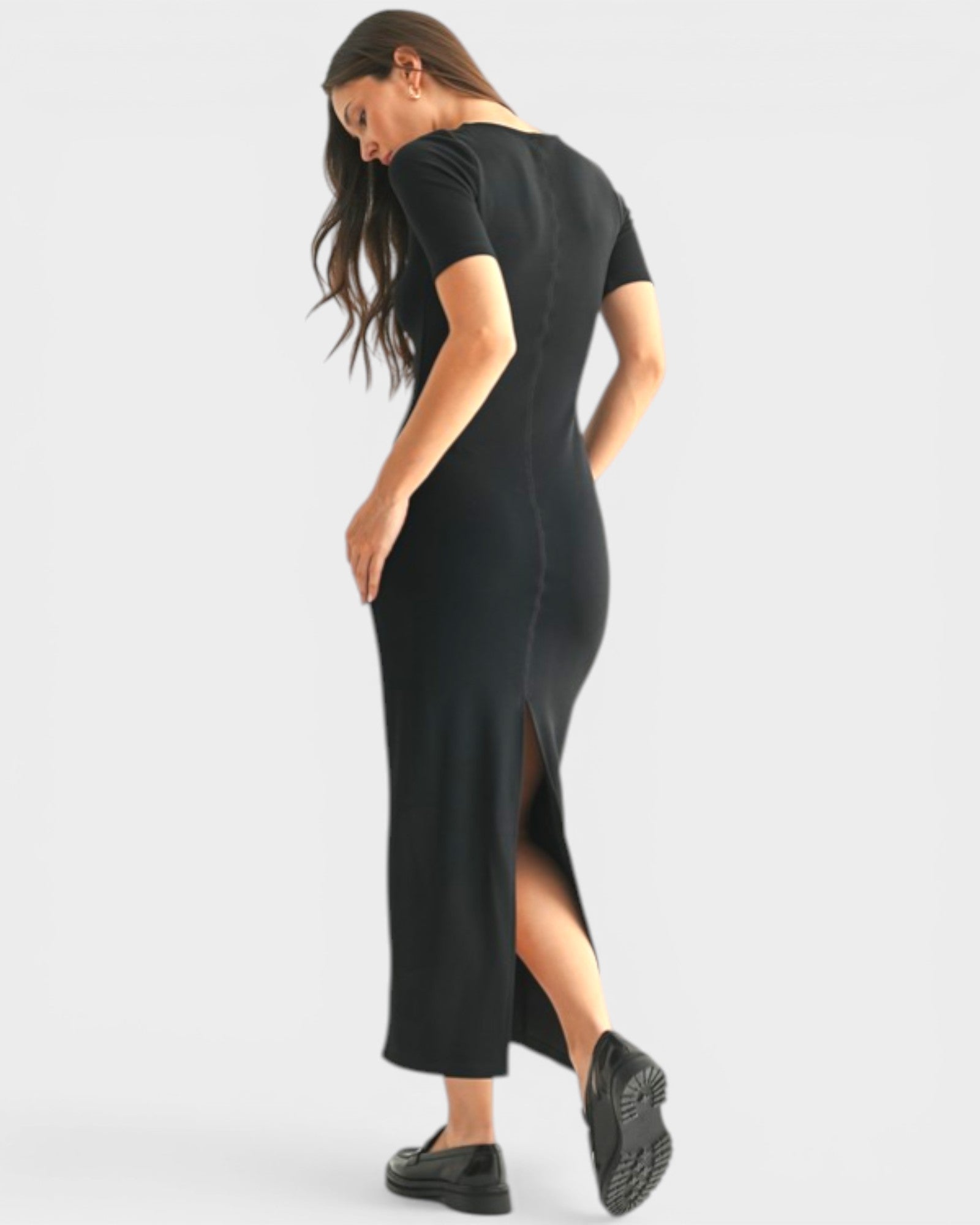 Woman wearing a black dress with a slit on a white background