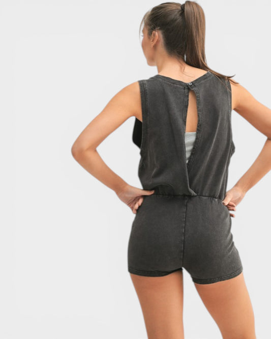 Woman wearing a black denim romper on a light gray background