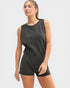 Woman wearing a black sleeveless top and shorts on a white background
