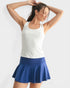 Woman wearing a white tank top and blue skirt on a light gray background