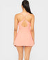 Woman wearing a peach-colored dress with cut-out back on a white background