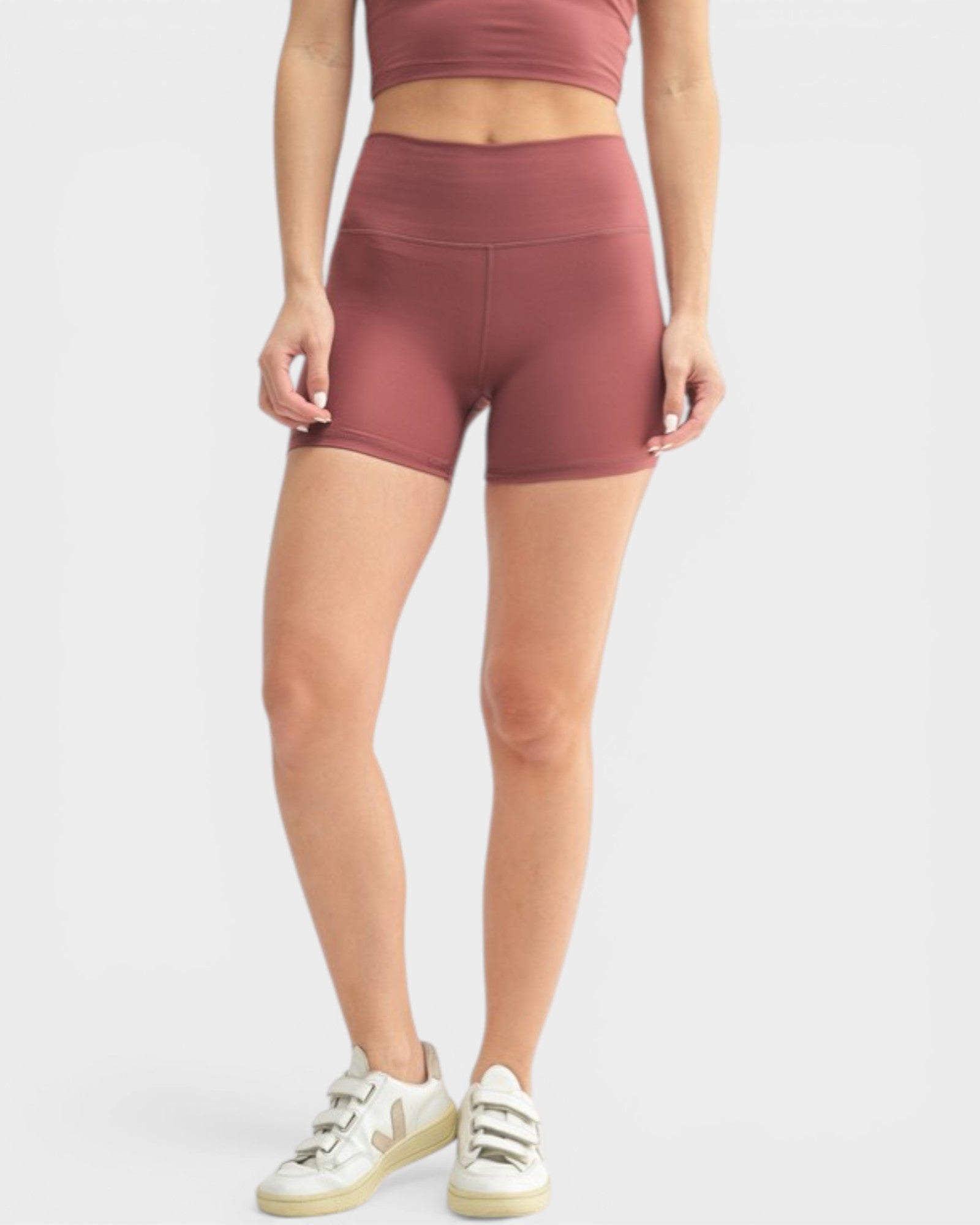 Person wearing maroon athletic shorts and top on a white background