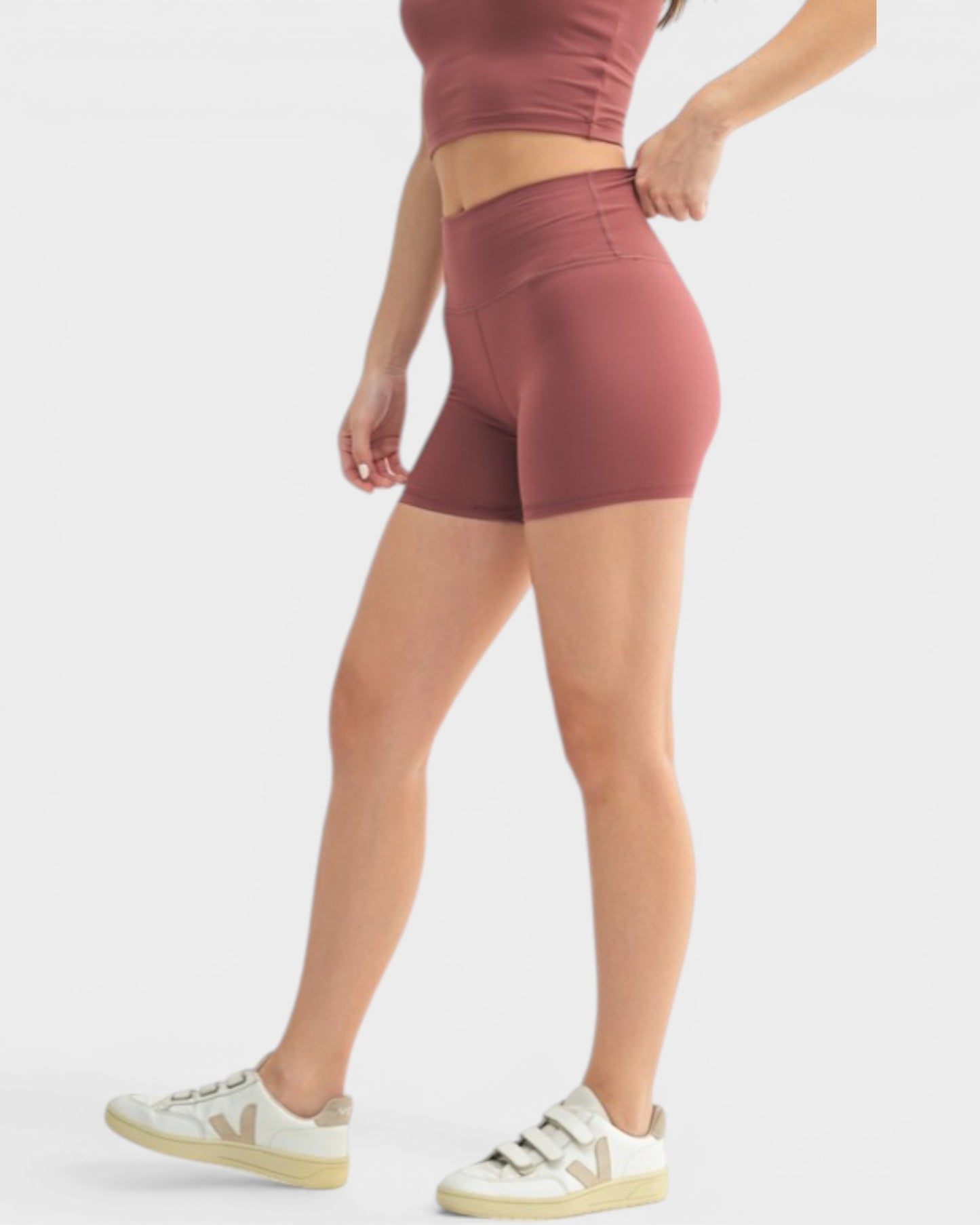 Person wearing maroon athletic shorts on a light gray background