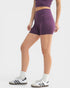 Person wearing purple athletic shorts and white sneakers on a white background