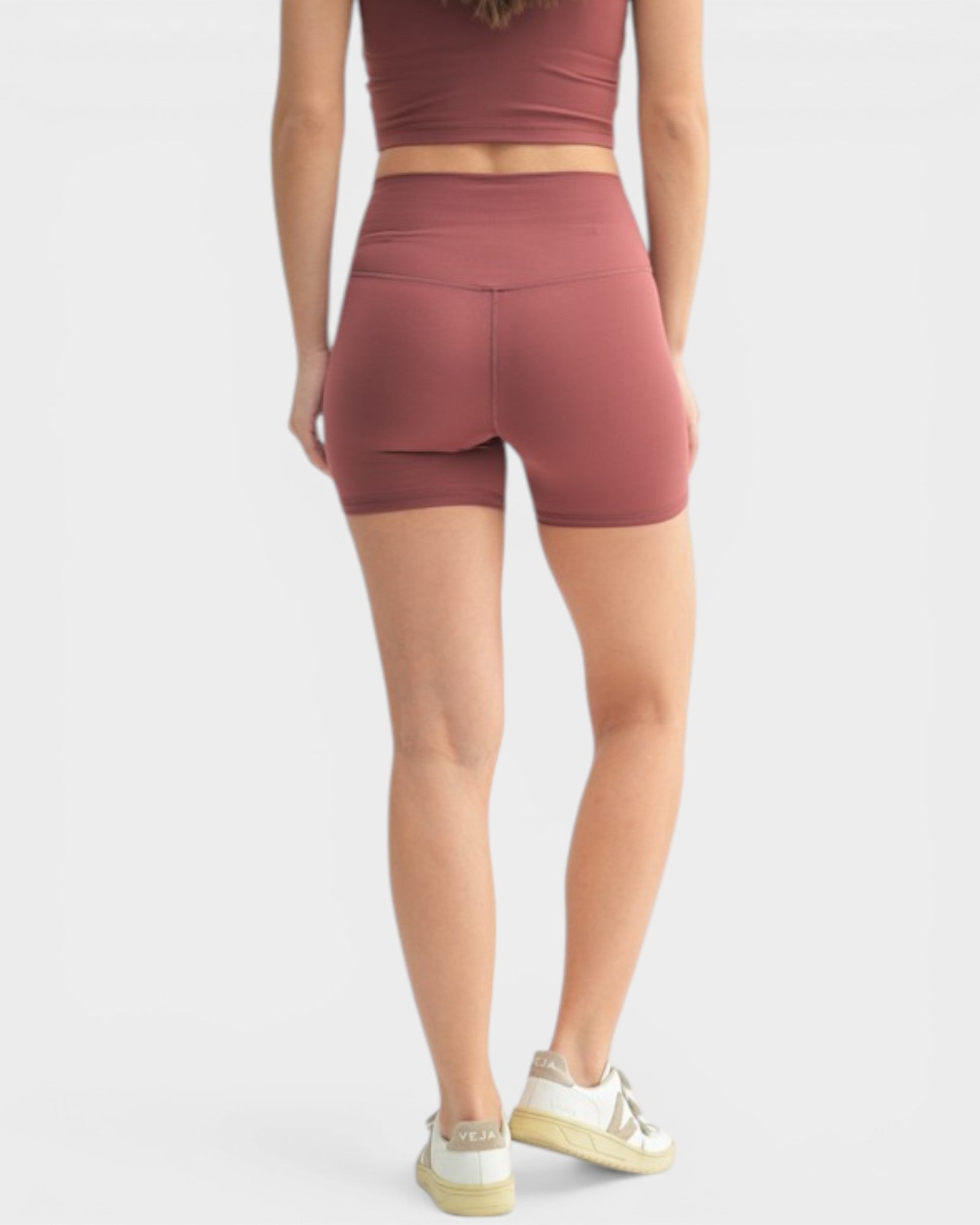 Person wearing a matching athletic outfit with shorts and top on a white background