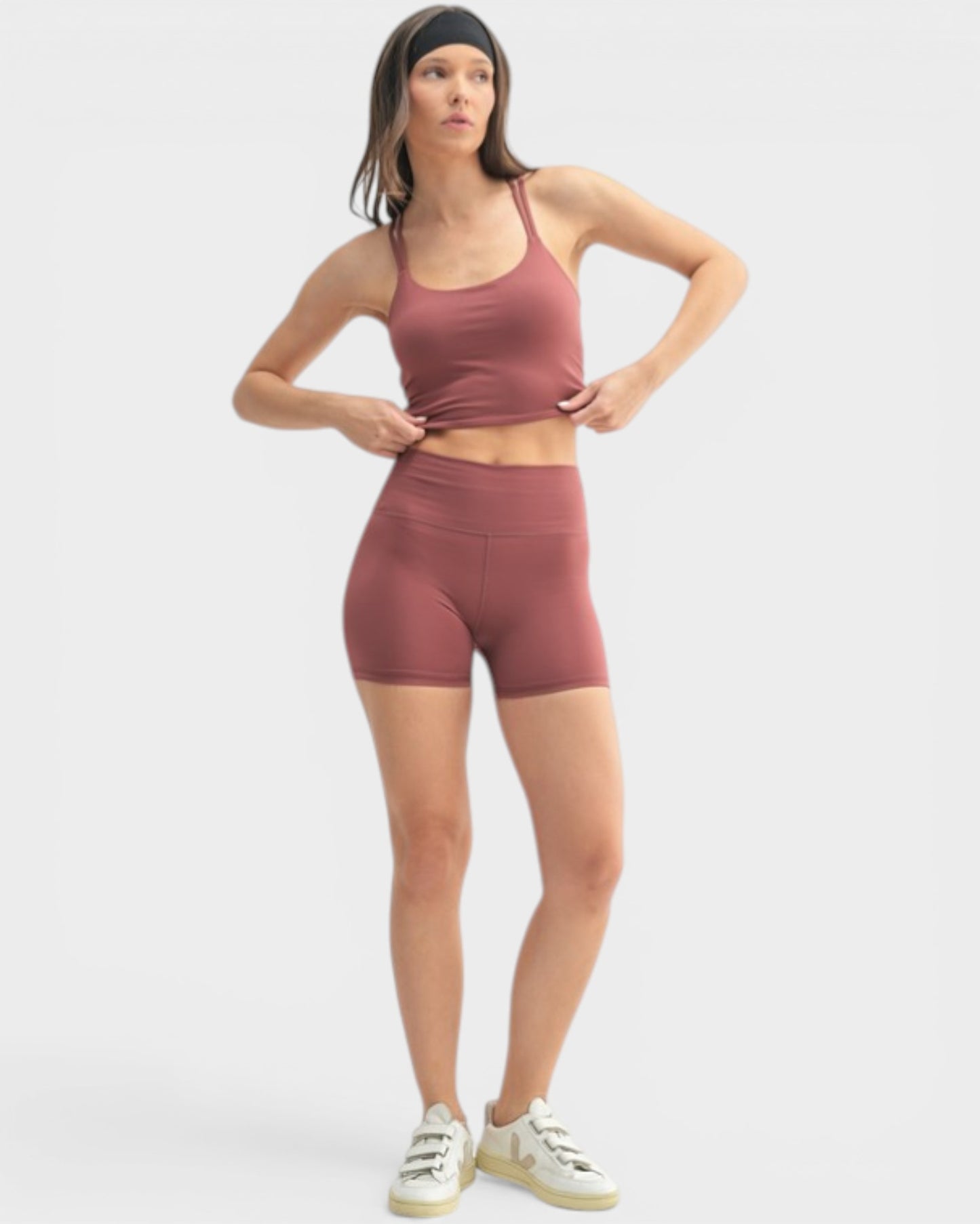 Woman wearing a maroon athletic outfit on a white background