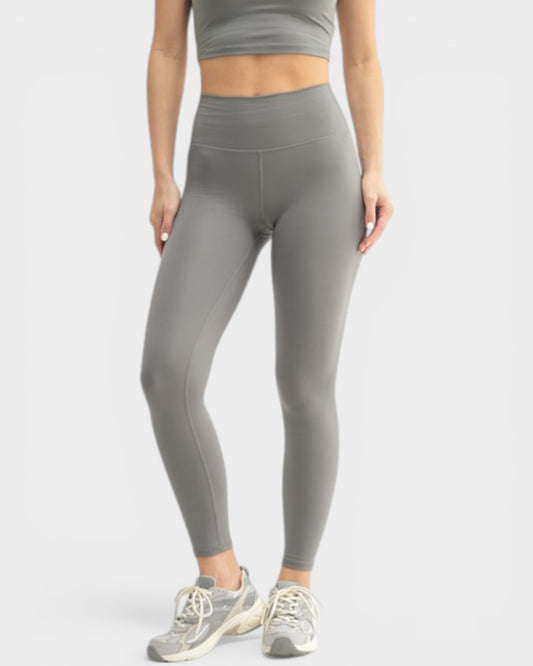 Person wearing gray leggings and a matching top on a white background